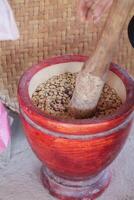 Farmers use wooden mortars and pestles to break the husks apart from the coffee beans to remove unwanted husks from coffee beans before processing them to produce high quality coffee beans for export. photo
