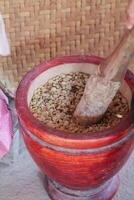 Farmers use wooden mortars and pestles to break the husks apart from the coffee beans to remove unwanted husks from coffee beans before processing them to produce high quality coffee beans for export. photo
