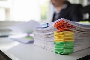 pile of documents sat on desk in office was pile of documents that had been prepared to be presented at meeting as summary of annual operations. Documents prepared for storage and piled on the desk. photo