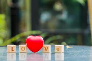 wooden blocks with word love are arranged to indicate meaning I love you and are also symbol of love and friendship for one another. Wooden blocks with word love are arranged on glass table. photo