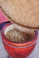 Farmers use wooden mortars and pestles to break the husks apart from the coffee beans to remove unwanted husks from coffee beans before processing them to produce high quality coffee beans for export. photo