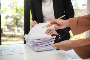 A pile of documents that the secretary has prepared for meetings of the company board of directors and investors. Many documents were arranged and prepared in piles on the desk in the secretary office photo