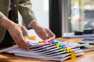 A pile of documents that the secretary has prepared for meetings of the company board of directors and investors. Many documents were arranged and prepared in piles on the desk in the secretary office photo
