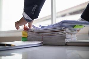 pile of documents sat on desk in office was pile of documents that had been prepared to be presented at meeting as summary of annual operations. Documents prepared for storage and piled on the desk. photo