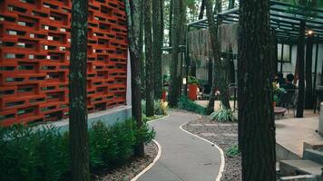 Serene outdoor cafe setting with a winding pathway, lush greenery, and modern wooden architecture, offering a tranquil environment video