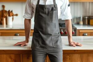 A chef stands in front of a counter with apron on photo