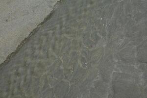 Abstract textured beach scene with wet sand and ocean waves photo
