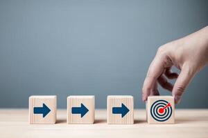 Businessman's hand holds a red dartboard symbol with an arrow pointing at target icon. concept of business defining mission, goals, and processes for success. photo