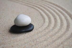 White and black zen stones on sand with customizable space for text photo