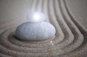 Zen stones with shining light on sand with customizable space for text or message photo