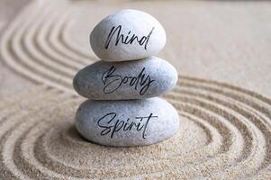 Mind, body and soul text on zen stones with bright light background photo