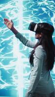 Vertical Developer wearing VR headset looking at hologram of artificial intelligence human brain simulation. Programmer interacting with AI visualization showing machine learning algorithms, camera B video