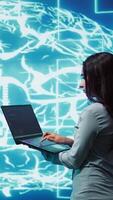 Vertical Computer scientist working on laptop, programming artificial intelligence computing simulating human brain. Woman using notebook, developing AI machine learning algorithms, camera B video