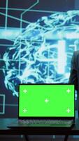 Vertical Teamworking AI technicians using green screen laptop for business data analysis. Team of IT experts works on mockup notebook to automatize tasks using artificial intelligence, camera B video
