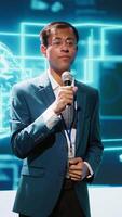 Vertical Presenter talking with spectators at AI convention bringing together IT specialists, sharing insights from latest developments in artificial intelligence and cognitive computing, camera A video