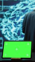 Vertical AI programmers colleagues using green screen laptop for business data analysis. IT experts in high tech location work on chroma key notebook to automatize tasks using artificial intelligence, camera B video