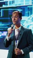 Vertical Presenter talking with spectators at AI convention bringing together IT specialists, sharing insights from latest developments in artificial intelligence and cognitive computing, camera B video