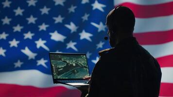 US Air Force dispatcher looking at surveillance transmission on device, relaying data to ground soldiers from control room using headset, isolated over United States flag background, camera A video
