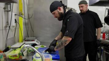 A professional male chef in a black uniform chops onions and other vegetables while starting to prepare a restaurant for work. Chefs work in the kitchen cutting vegetables and preparing dishes video