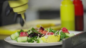 Close up a cook in black protective gloves sprinkles a salad with white sauce Before serving and presenting a dish in the kitchen in a restaurant video