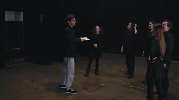 A confident young brunette man with glasses, a director with papers in his hands tells the actors about his plot and how to behave correctly during preparation and rehearsal on the theater stage video