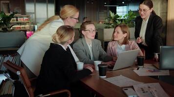 Confident group Business Woman in business clothes sitting at a table in the office in front of a laptop and communicating about solving their problem and current ideas about work In the office video