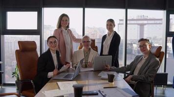 Portrait of a group of confident girls in business suits wearing glasses at a table during a meeting in a modern office with large windows video