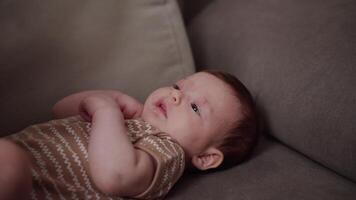 Close up of a little girl child baby lying on a gray sofa and being played with using a small soft toy for children at home video