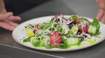 Up close a professional chef presents his dish and spins it in a circle for a full view of the salad and all its details on the table in the kitchen of a restaurant video
