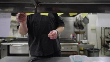 A male professional chef lays out orders and gives the dish to the waiters while he is working in the kitchen at the table. A male chef lays out stickers with orders from the hall for preparing dishes video