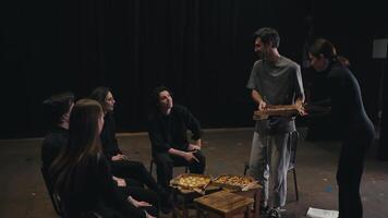 Confident actors in black uniforms together with their director ordered pizza to the theater during a rehearsal and communicate with each other while preparing for the performance on stage video