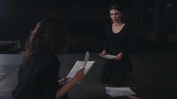 A brunette girl communicates with her colleague while acting out her role in the theater and preparing the text and script for a performance on stage in an empty theater video