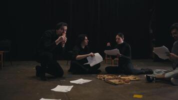 Confident actor brunette girl in a black suit communicates with her colleague about the script holding sheets of papers in her hands along with her director on stage at a rehearsal in the theater video