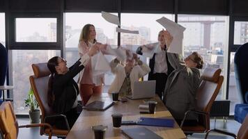 A group of happy businesswoman colleagues in business suits throw up sheets of paper in the name of their Victory and success while working in the office at the table video