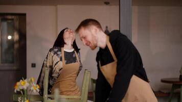 A happy brunette girl communicates with a guy waiter while they are working together and preparing to clean the cafe hall video