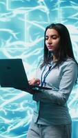 Vertical Software developer solving tasks on laptop, running artificial intelligence programming scripts. Woman using notebook to write lines of code for AI applications development, camera A video