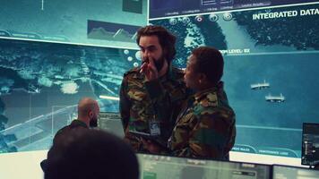 Diverse team of army officers reviewing important information from the enemy lines, ensuring advantage in a military command center. People using satellite surveillance in power base. Camera B. video
