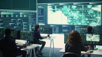 Group of governmental hackers using hacking tools to secure a network, focusing on cyber defense and data protection measures. Experts team examining important information on big screen. Camera B. video