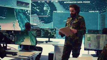 Army major reads operation details from a case file in a control center military headquarters, manages personnel and resources for logistical or operational missions. Task force command. Camera B. video