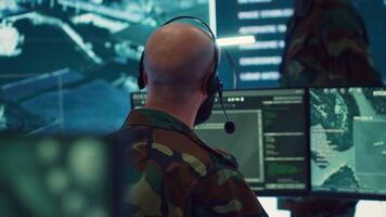 Male IT specialist operating on reconnaissance system to transmit real time data for new field mission, working in military command center. Telecommunications operator provides air support. Camera A. video