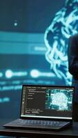 Vertical Focus on laptop in workspace used by AI researchers working with artificial intelligence in blurry background. Close up of notebook used by employees developing AI systems in tech startup, camera A video