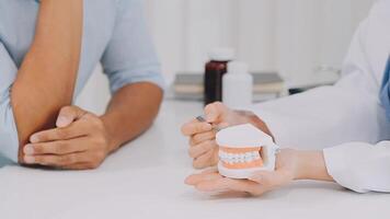 Dentist consultation - patient visit at the dental clinic office. Female dentist wearing dentures to explain teeth Recommend guidelines for orthodontics Dentist giving advice on patient's condition. video