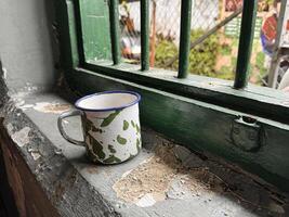 The old tin cup utensils on the table in the Asian prison ward, local called as cangkir blirik, drinking tin cup used in Asian prisons some old days photo