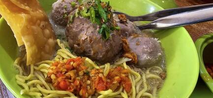 Giant Bakso, or Jumbo meatball is indonesian meatball style served with beef broth soup and noodle springkled with fried onion and spring onion coupled with chili sauce on the top photo