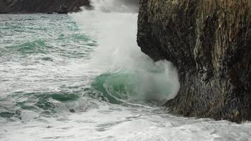 Stormy sea on sunset. The waves crash into the volcanic basalt rock, lit by the warm sunlight. Big wave breaks into splashes and white foam. Never-ending beauty of nature. Slow motion. video