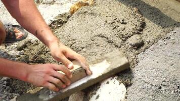 Construction, Worker Hands smooth wet cement in wooden frame at a construction site during daytime to ensure an even surface video