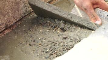Construction, Worker Hands smooth wet cement in wooden frame at a construction site during daytime to ensure an even surface video