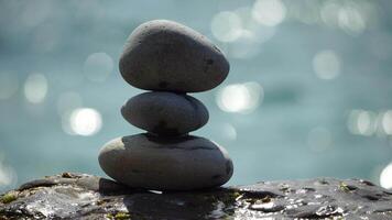 Pyramid stones on the seashore on a sunny day on the blue sea background. Happy holidays. Pebble beach, calm sea, travel destination. Concept of happy vacation on the sea, meditation, spa, calmness. video