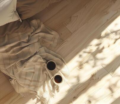 A top-down view of two cups of coffee resting on a folded blanket, illuminated by warm sunlight streaming through a window photo