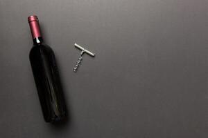 One Bottle of red wine with corkscrew on colored table. Flat lay, top view wth copy space photo